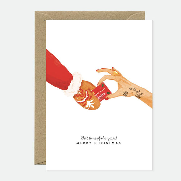 Greeting card showing Santa’s gingerbread hand handing over a festive credit card, blending Christmas cheer with humor.