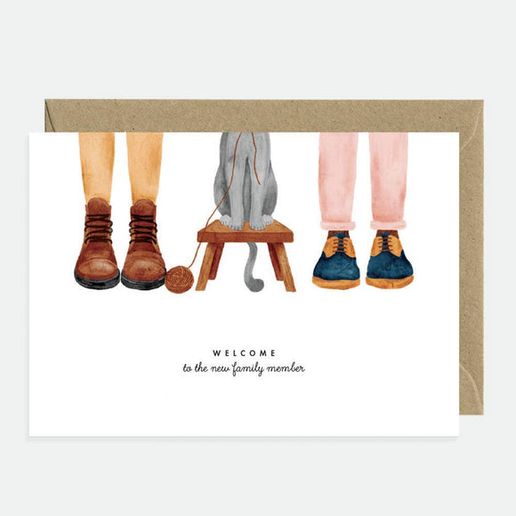 Greeting card with an illustration of cat paws and human hands in a welcoming message, paired with a brown envelope.