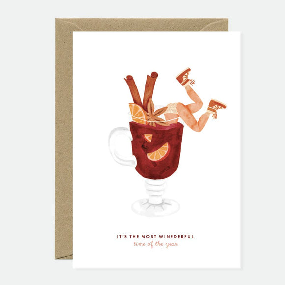 Greeting card with an illustration of a glass of red wine, a book, and a cartoonish character relaxing, with the text 'It's the most wonderful time of the year'.