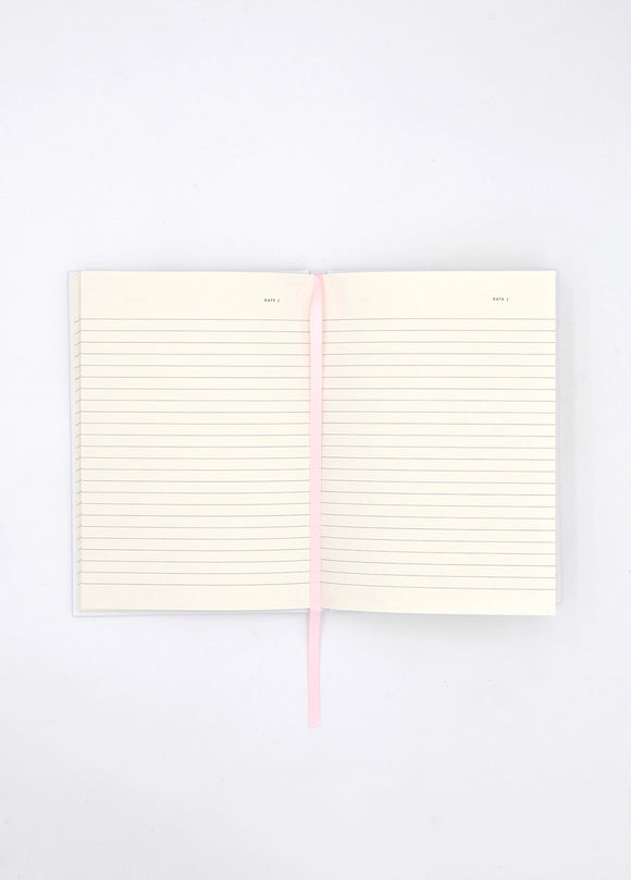 Open Dogue notebook showing lined cream pages with pink ribbon bookmark for writing and journaling.