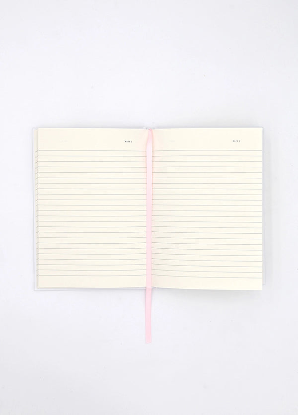 Open Dogue notebook showing lined cream pages with pink ribbon bookmark for writing and journaling.