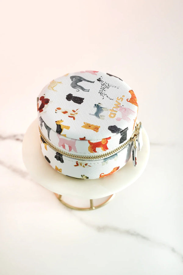 Round jewelry box with colorful dog illustrations, zip closure, displayed on a marble stand