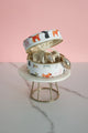 Open round jewelry box with dog pattern, showing interior storage and golden jewelry pieces