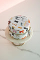 Round jewelry box with colorful dog illustrations, zip closure, displayed on a marble stand