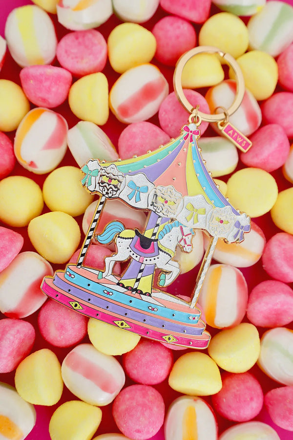 All The Ways To Say carousel keychain with gold details and pastel candy colors – playful flatlay