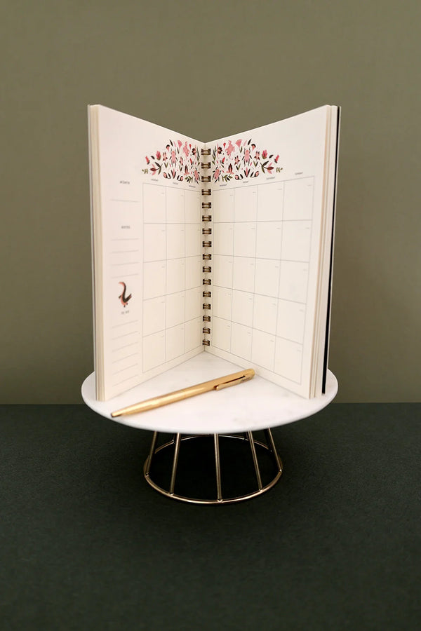 Open Pink Croco monthly planner standing upright showing monthly spread with floral decoration