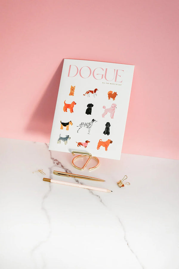 Cover of the Dogue monthly planner featuring colorful watercolor dog illustrations against a pink background with gold stationery.
