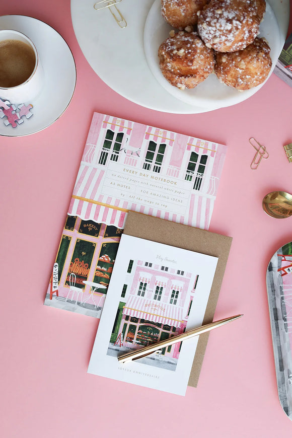 Close-up of pink bakery notebook cover with striped awning and golden details — eco-friendly stationery by All the Ways to Say.