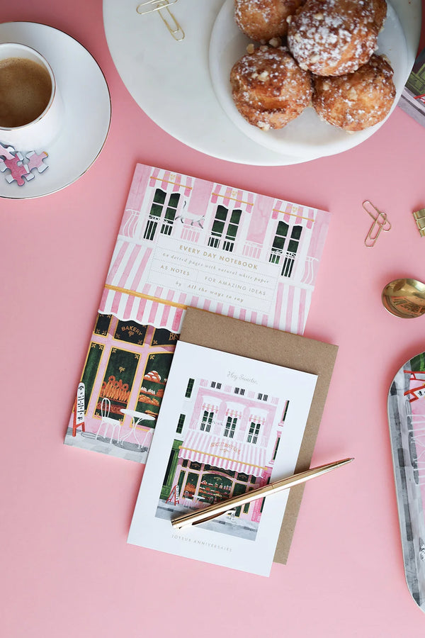 Close-up of pink bakery notebook cover with striped awning and golden details — eco-friendly stationery by All the Ways to Say.