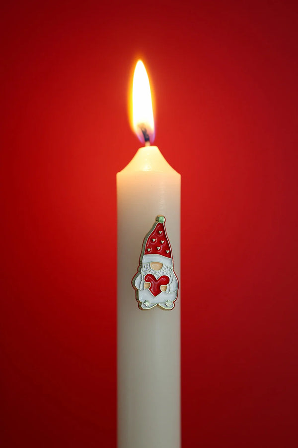 Grumpy Heart enamel pin by All The Ways To Say on white candle with red background – festive Christmas mood