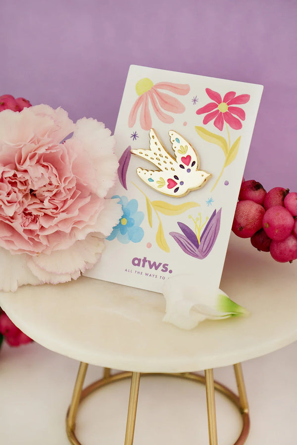 Lovebird enamel pin by All The Ways To Say on floral illustrated card – pastel purple backdrop and soft lighting