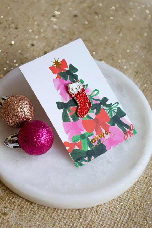 Cat Sock enamel pin by All The Ways To Say on illustrated Christmas card with pink and red bows – holiday setting