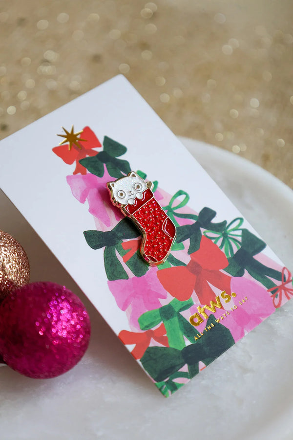 Close-up of Cat Sock enamel pin by All The Ways To Say – red stocking with cute cat face, holiday edition
