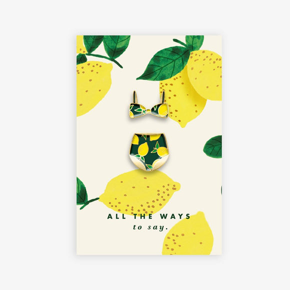 Lemons Swimsuit enamel pins set by All the Ways to Say featuring lemon-print bikini top and bottom with gold-plated details on citrus-themed background.