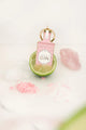 Pink glitter gin bottle keychain resting inside a cut lime with pink salt and ice blocks.