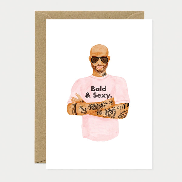A humorous greeting card by All The Ways To Say featuring a watercolor illustration of a bald man with sunglasses and tattoos wearing a pink "Bald & Sexy" t-shirt.