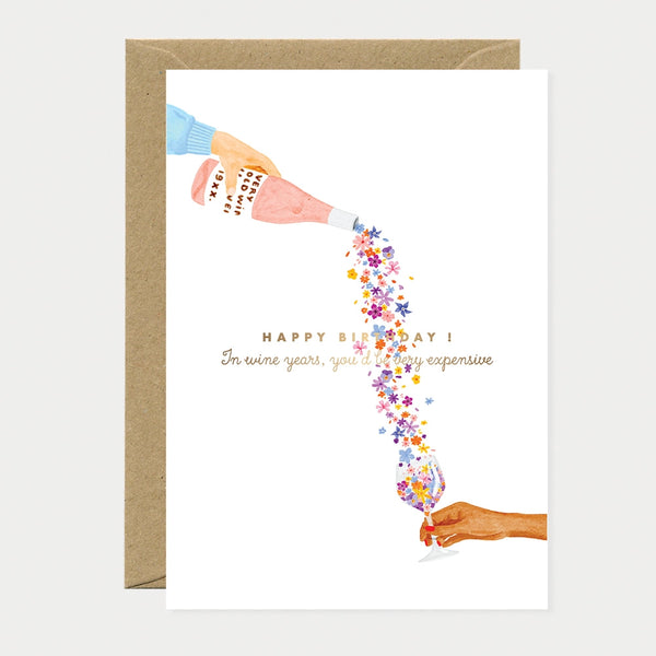 A poetic watercolor greeting card by All The Ways To Say showing a hand pouring a stream of flowers from a wine bottle into a glass with a birthday message.