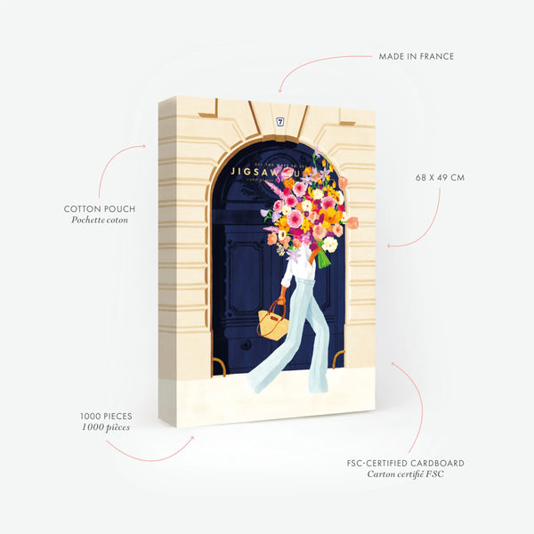 Product features of the Parisian Door 1000-piece jigsaw puzzle. Highlights: 68x49 cm size, FSC-certified cardboard, and Made in France. The illustration depicts a woman in chic white jeans carrying a massive colorful bouquet in front of a classic navy blue Paris door.