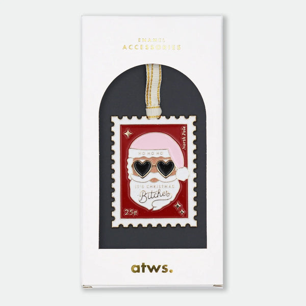 Gold-tone enamel Christmas ornament shaped like a postage stamp featuring Santa Claus wearing heart-shaped sunglasses, text reading "Ho Ho Ho, It's Christmas Bitches," "North Pole," and "25¢"