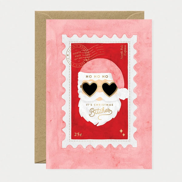 Illustrated Christmas card designed as a postage stamp featuring Santa Claus wearing heart-shaped sunglasses, gold foil postmark reading "North Pole, 25th Dec" and "North Pole Express," text reading "Ho Ho Ho, It's Christmas Bitches" with "Bitches" in gold foil script, and a "25¢" stamp value in the corner