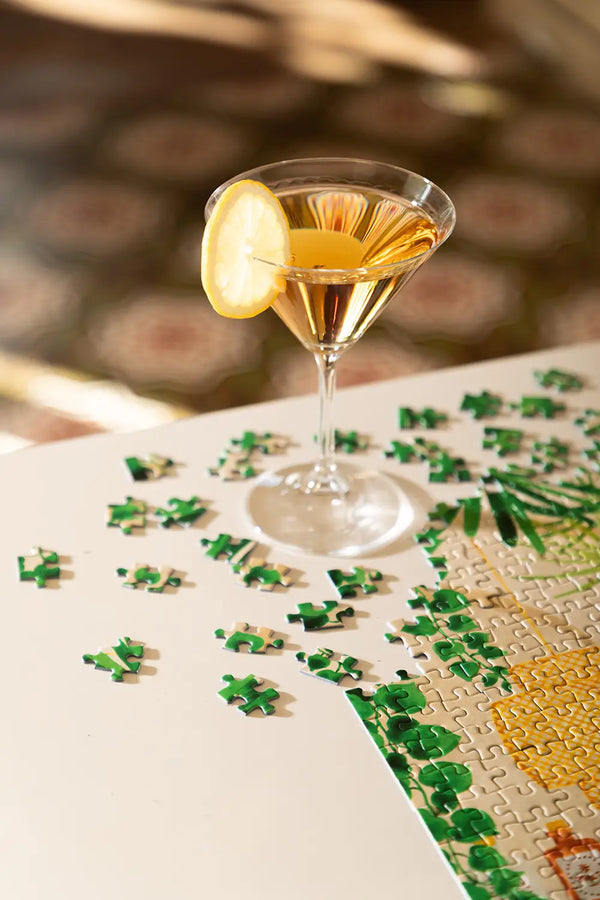 Bar - Puzzle 1000 pieces: a martini glass with a lemon slice set against scattered green puzzle pieces.