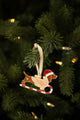 Dachshund enamel Christmas ornament with a Santa hat and heart sunglasses, "Merry Woofmas" sweater, riding a candy cane sled on a lit tree