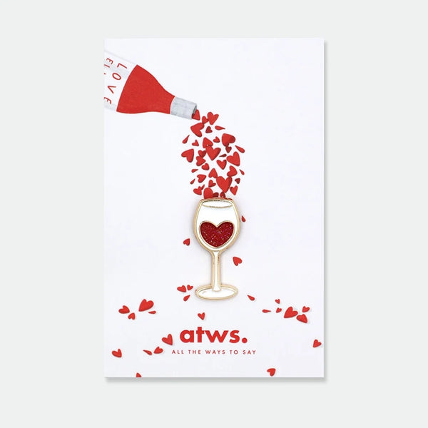 Enamel pin shaped like a wine glass with a red glitter heart inside