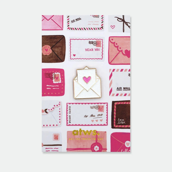 Enamel pin of a white envelope with a glitter pink heart peeking out