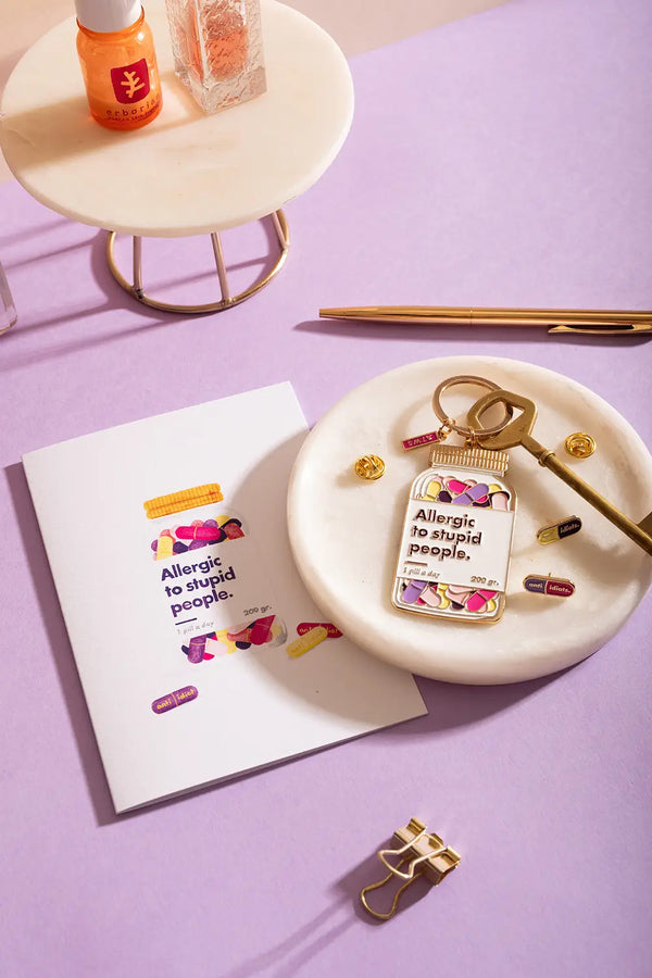 Allergic to stupid people Greeting card - Lifestyle view with matching keychain and pins on a purple background.