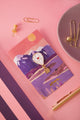 Hot air balloon enamel pin with a red heart and a dangling gold basket on a chain, on an illustrated mountain lake backing card