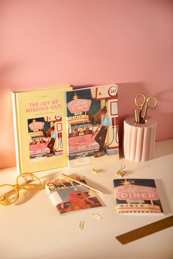 Jomo A5 hardcover notebook with matching California Diner notebooks and a "Chic b*tch" mini notebook on a desk