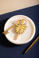 Beach please Keychain - Top view of the yellow and gold palm tree design on a white marble background.
