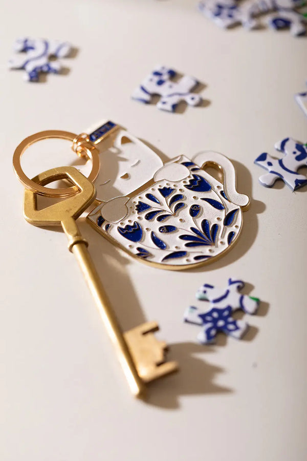 Cat in a mug Keychain - Perspective shot showing the golden metal edges and enamel finish.