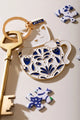 Cat in a mug Keychain - Detailed focus on the cat's face and the intricate blue mug patterns.