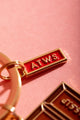 Chit chat Keychain - Focus on the small red and gold ATWS logo charm on the ring.