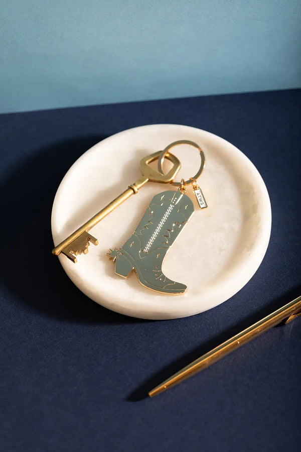 Cowboy Boot Keychain - Golden boot illustration on a white marble tray with a vintage key.