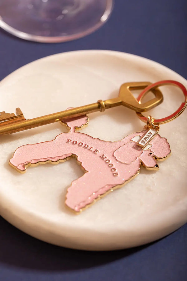 Poodle mood Keychain - Top view of the pink poodle design with a vintage key on white marble.