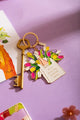 Rosay day Keychain - Lifestyle view on a purple background with a vintage key and "Thanks" greeting card.