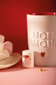 Love Mugs enamel pin showing three stacked cups in red, peach and pink with hearts, on a marshmallow next to a "Mon amour" mug