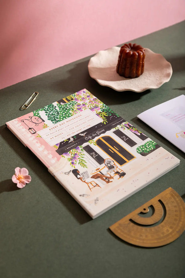 Notebook A5 Paris - Lifestyle view of the "Café des Fleurs" illustration on a green desk.