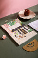 Notebook A5 Paris - Lifestyle view of the "Café des Fleurs" illustration on a green desk.