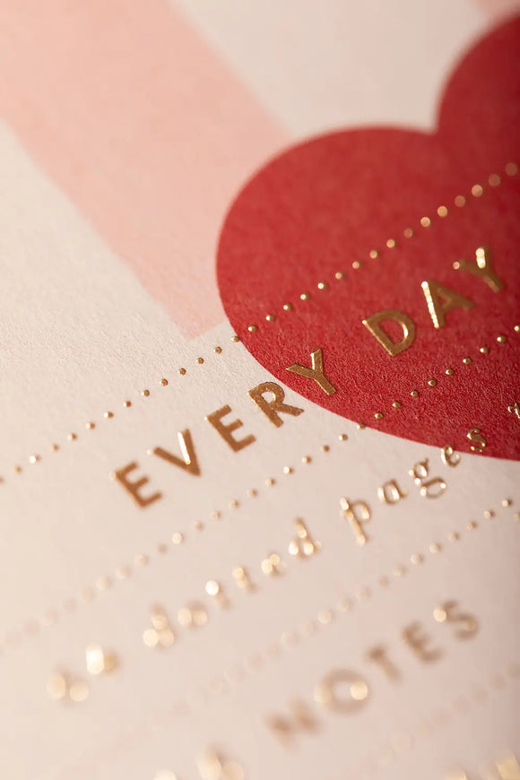 Pink stripes Notebook A5 - Macro shot of the gold foil "Every Day Notebook" title and red heart.