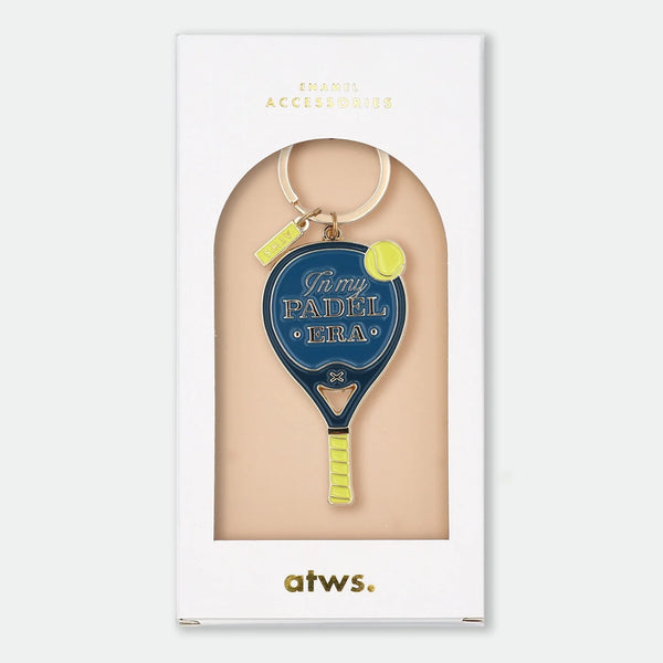 Enamel and metal keychain shaped like a navy blue padel racket with a yellow tennis ball, text reading "In my padel era," gold-tone ring and "ATWS" charm