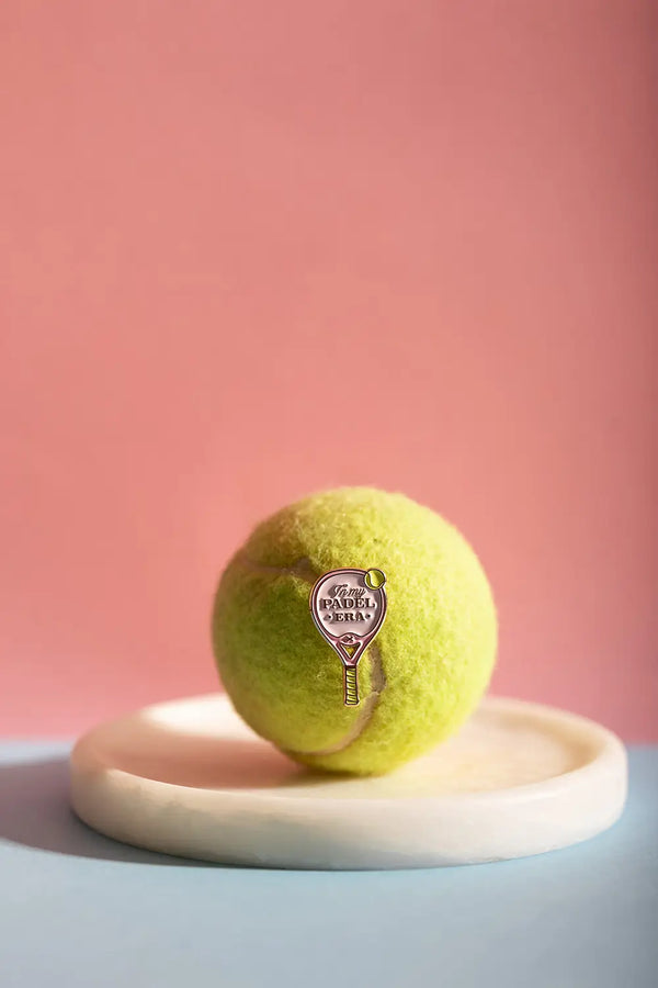 Padel Era - Pins: a pink and gold padel racket enamel pin displayed on a yellow tennis ball.