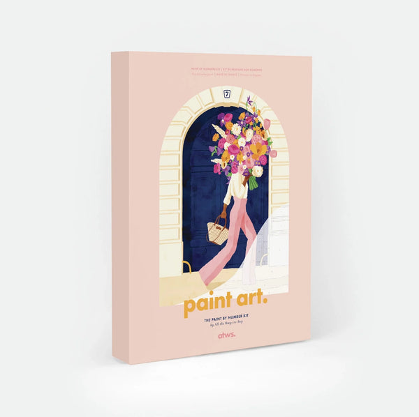Parisian Door paint by numbers kit box by All The Ways To Say, illustration of a woman walking away from a blue Parisian doorway numbered 7, carrying a large bouquet of flowers and a woven basket, "paint art. The Paint By Number Kit by All The Ways To Say"