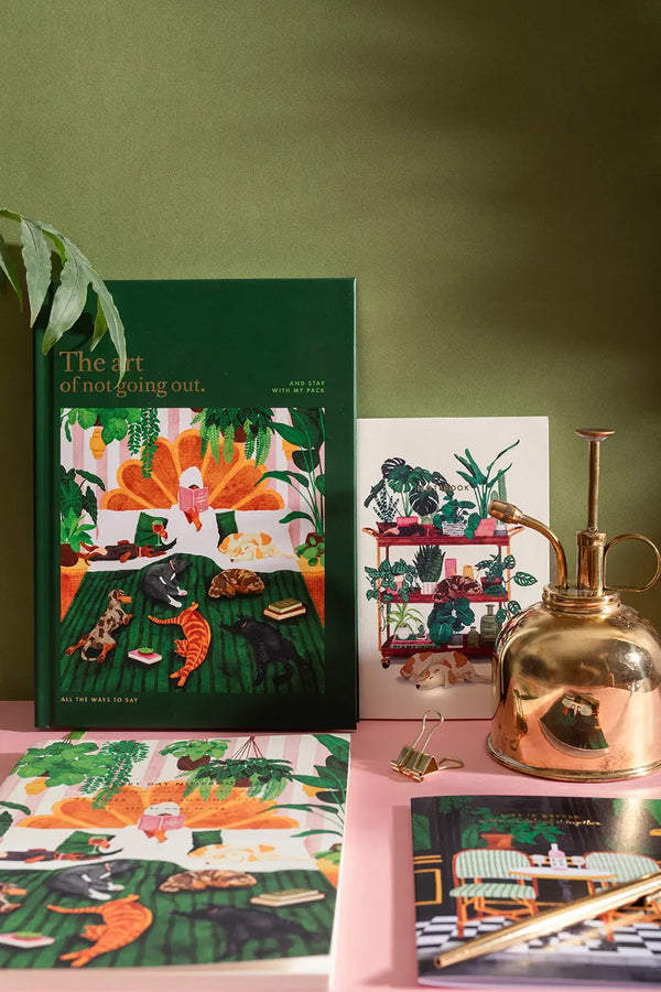 LIFE WITH PETS & PLANTS - Collection: high-angle shot of the "Art of Not Going Out" green journal and cat-themed stationery.