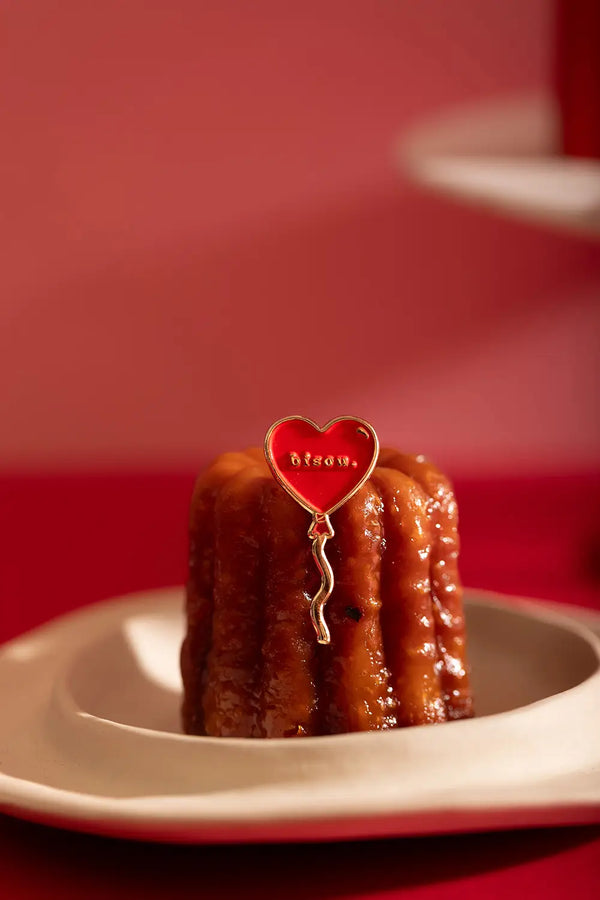 Bisou Enamel Pin - Red heart balloon pin stuck in a French cannelé pastry.