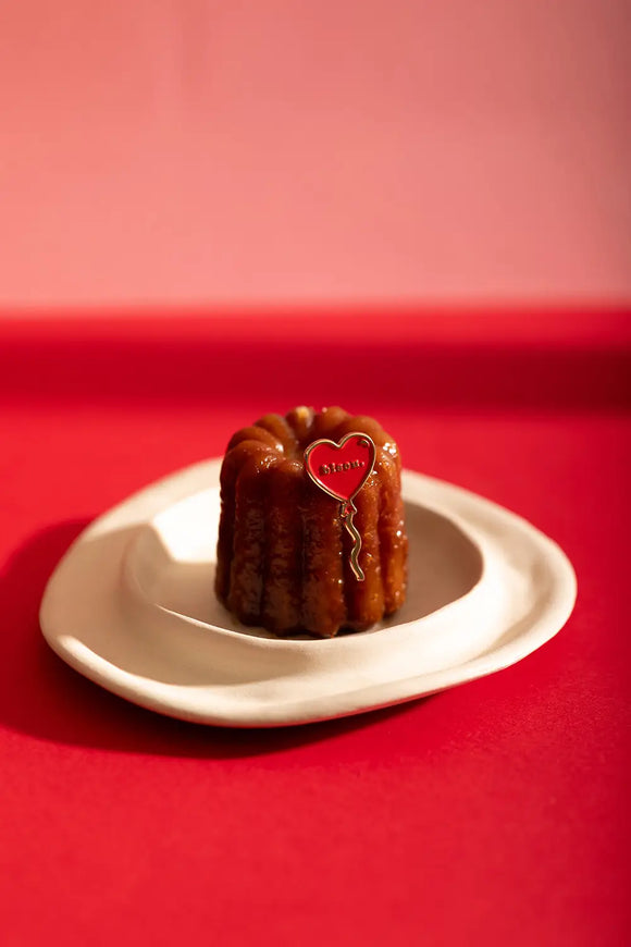 Bisou Enamel Pin - Wide lifestyle view of the heart pin on a pastry and white ceramic plate.