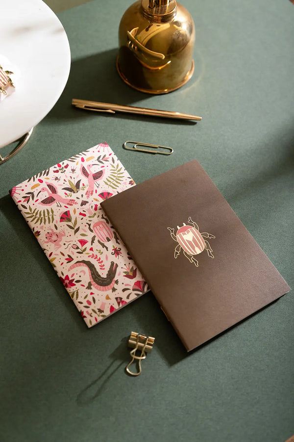 Pink Croco Pocket Notebook A6 DUO - Lifestyle view on a green desk with gold accessories.