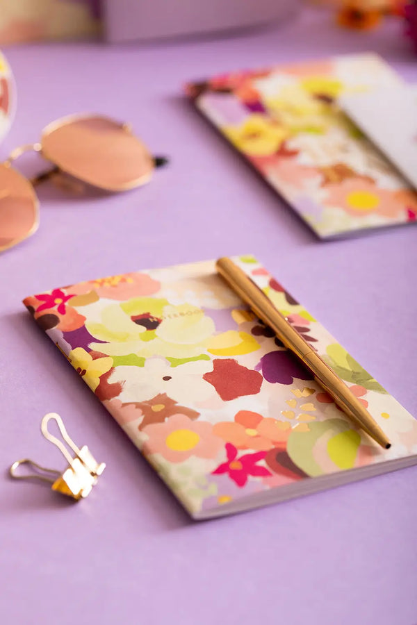 Spring Sweets Pocket Notebook A6 DUO - Lifestyle view on a purple background with a gold pen.